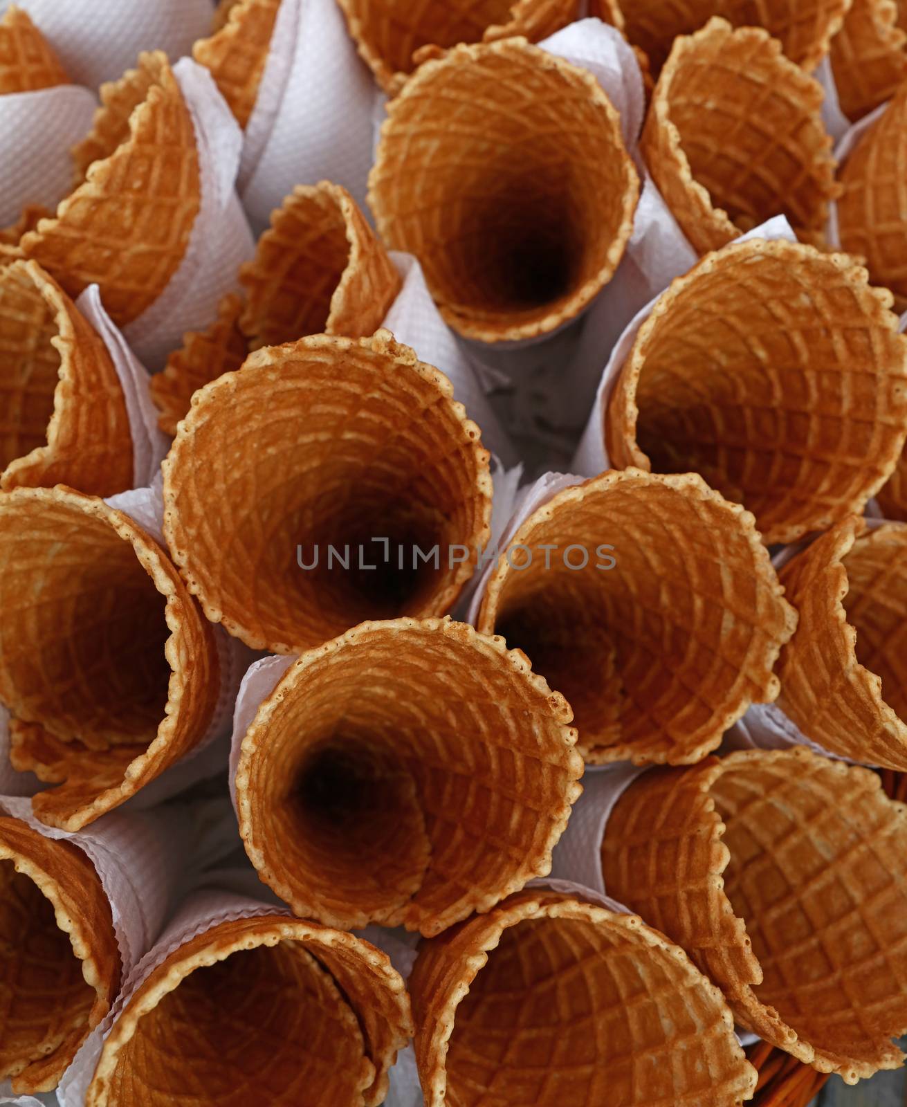 Several empty fresh wafer ice cream cone cornet cups with white paper napkins, close up, elevated high angle top view, directly above