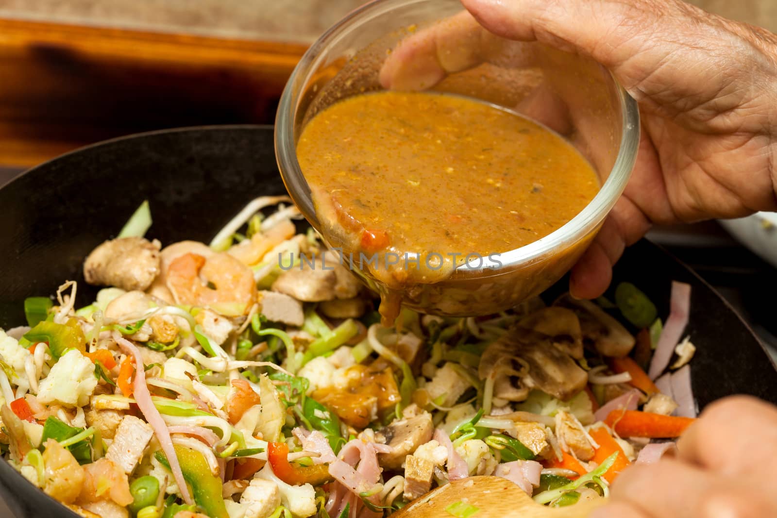 Sauteed vegetables with chicken, pork, jam and shrimps preparation : Adding sauce to the vegetables and meats into a wok