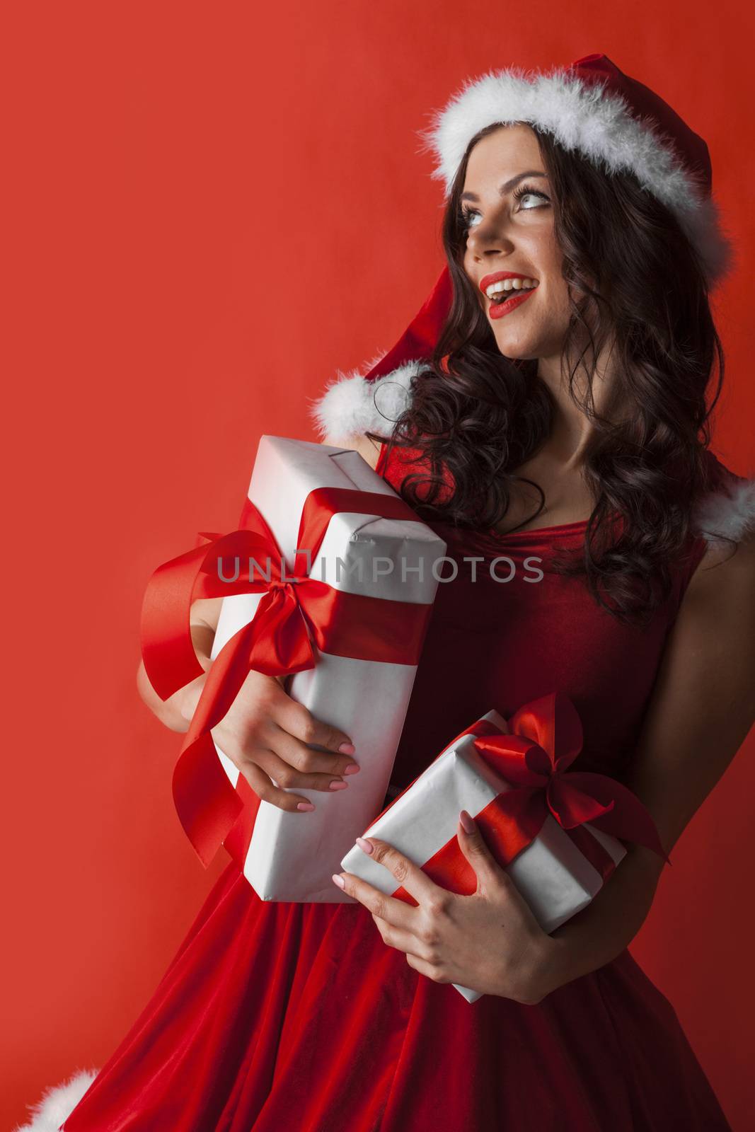 Excited surprised woman in red santa claus outfit holding Christmas presents