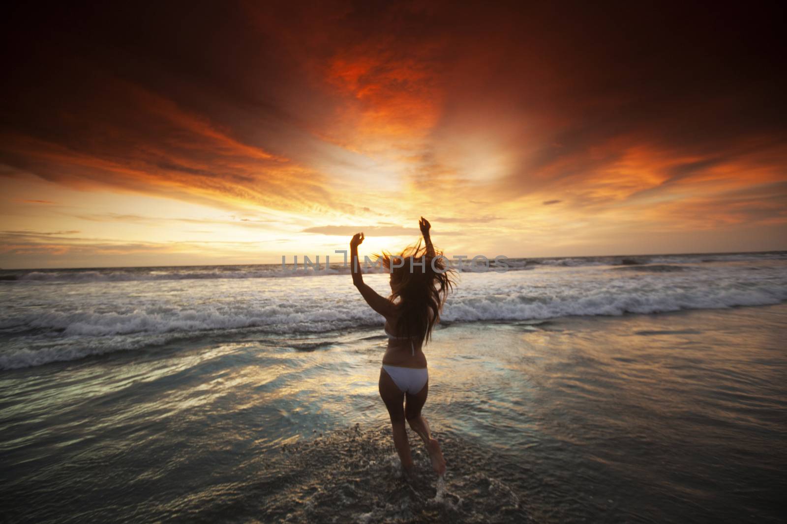 Happy Woman in bikini Jumping in Sea Sunset