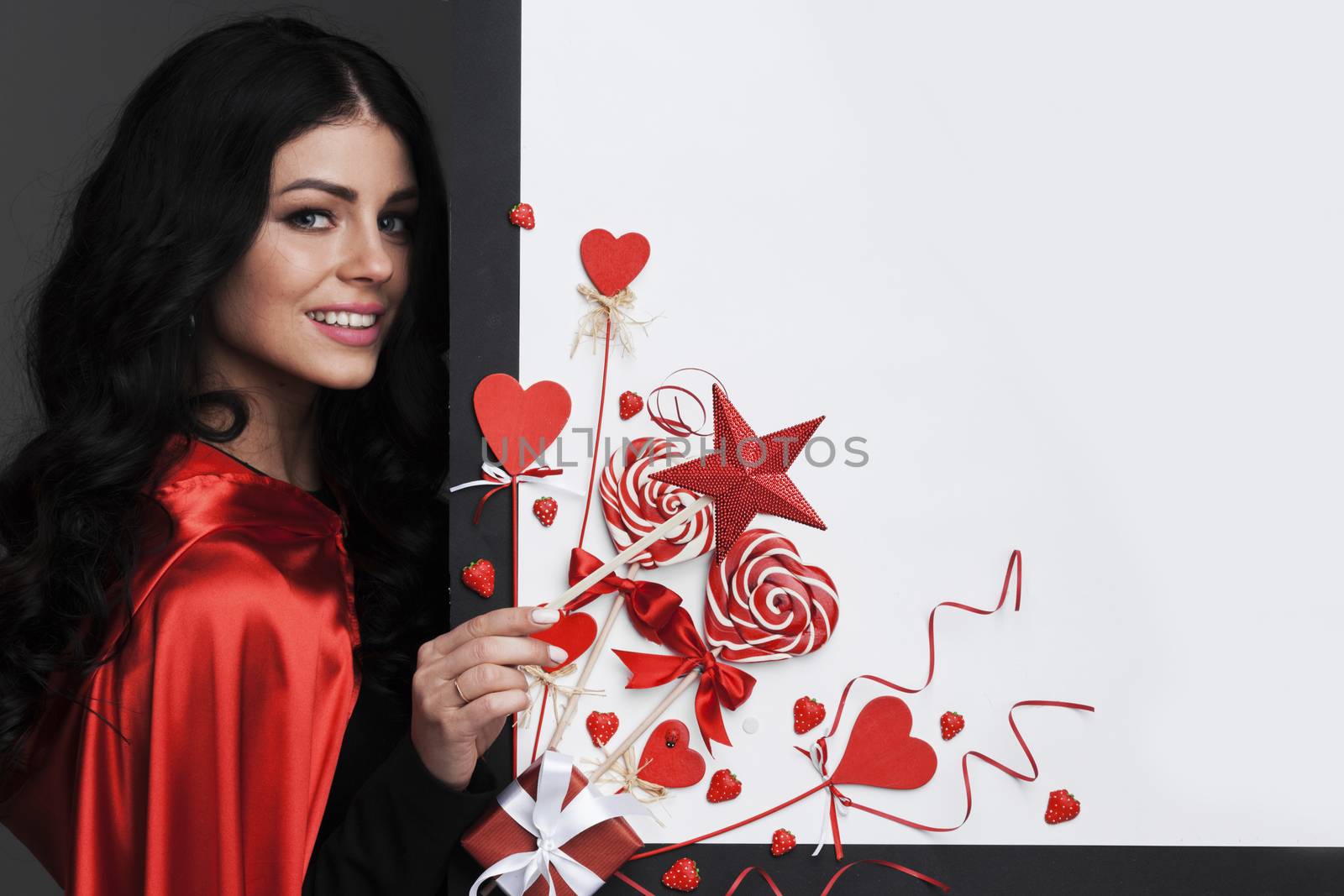 Woman with magic wand near Valentines day decoration and heart shaped lollipops isolated on white background