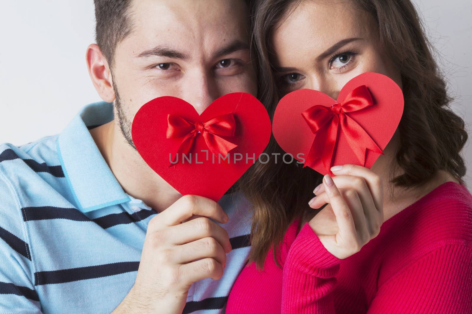 Young couple celebrating Valentine day holding paper heart cards