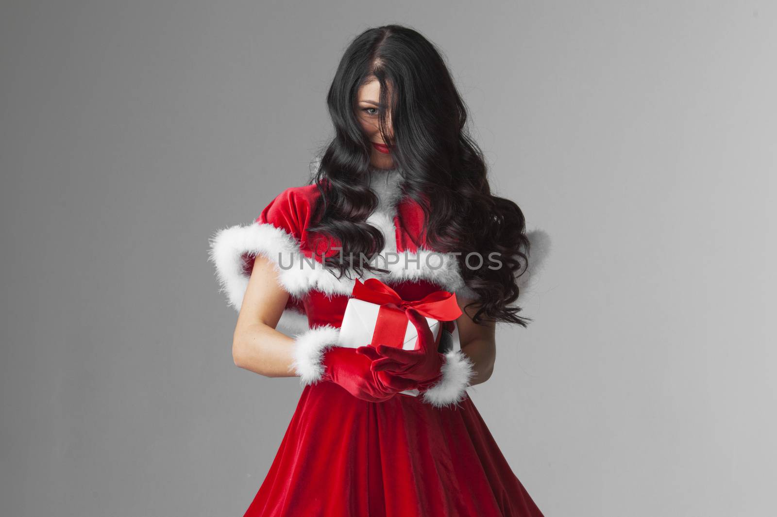Excited surprised woman in red santa claus outfit holding Christmas present