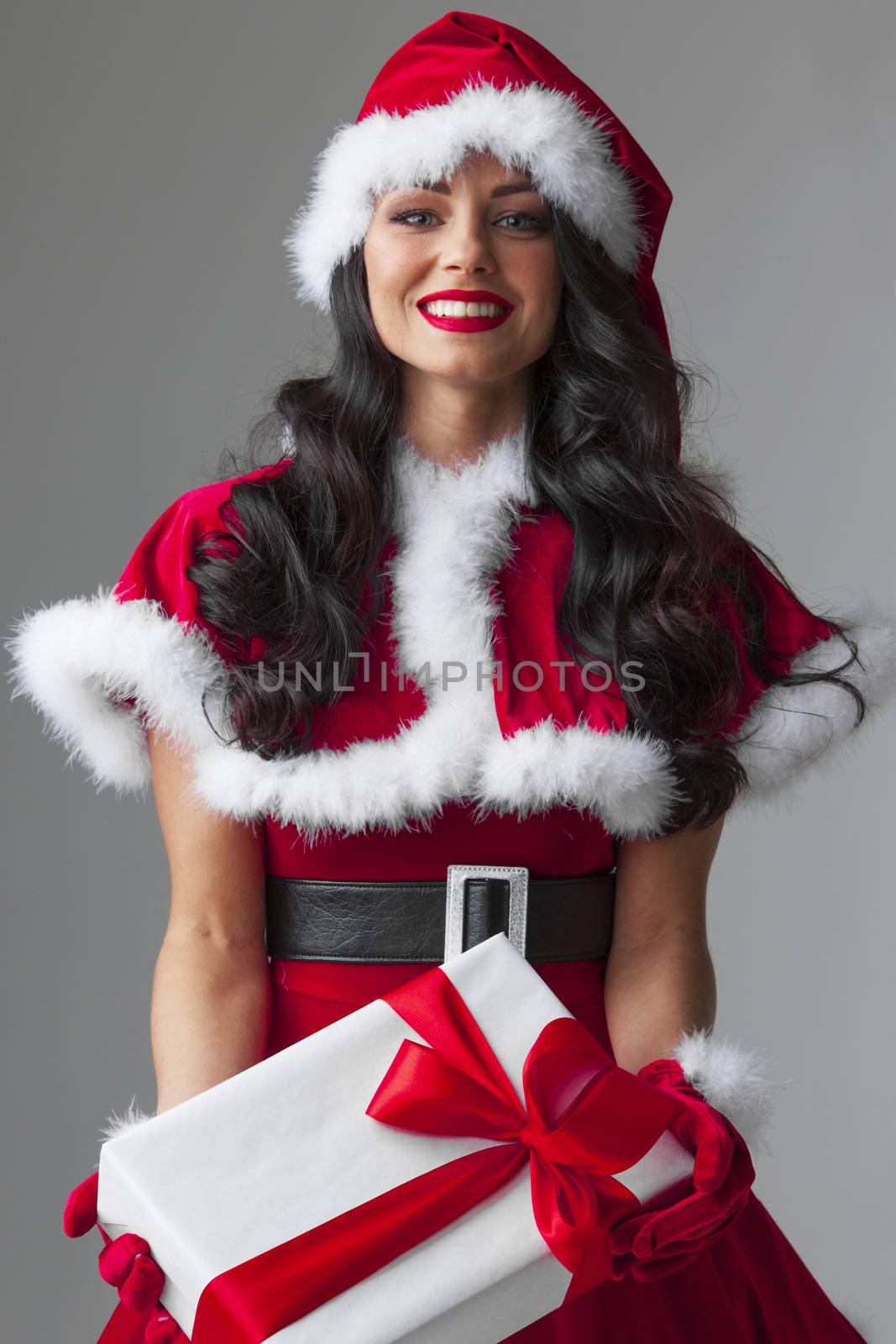 Excited surprised woman in red santa claus outfit holding Christmas present