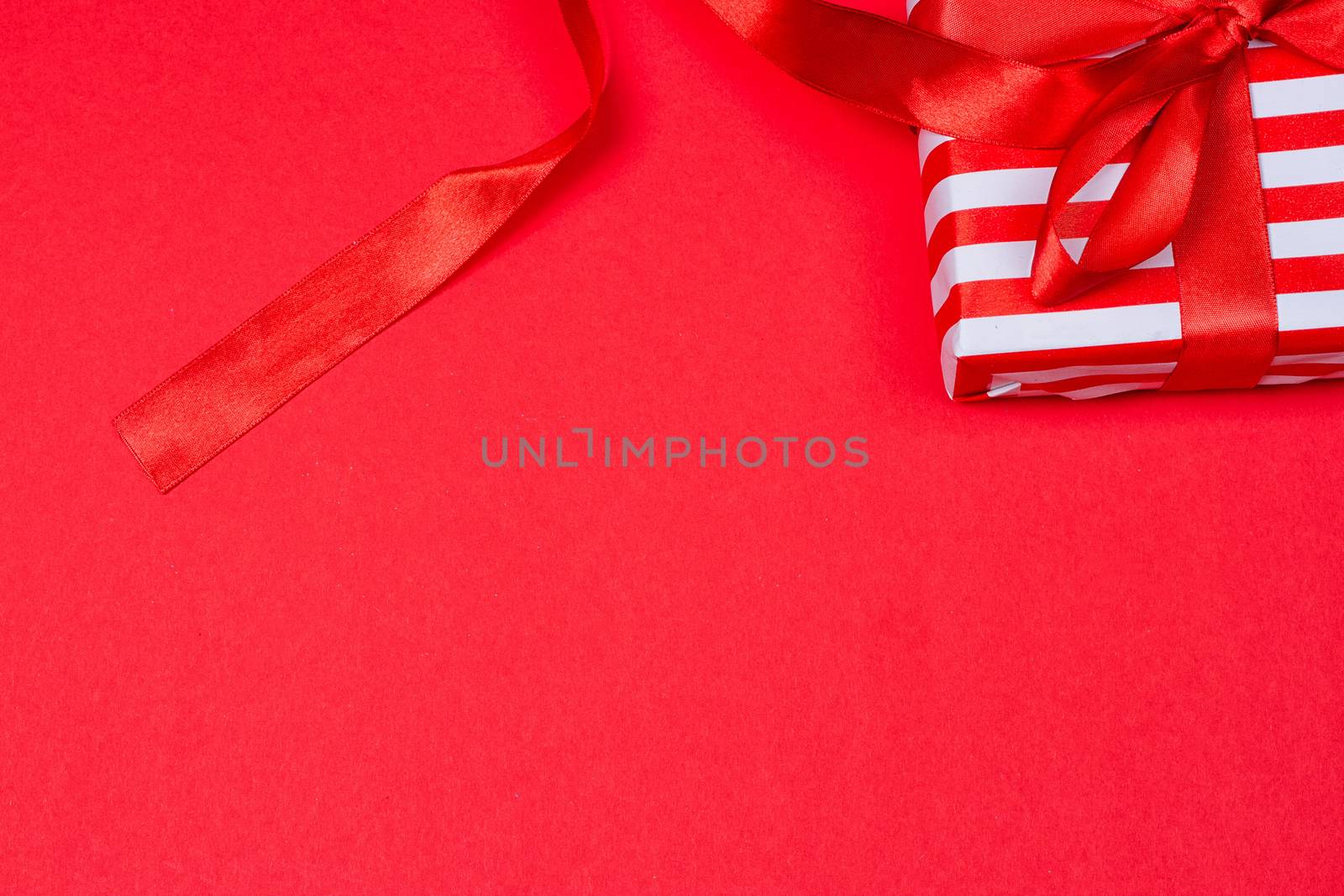 gift with red bow on red background. Free space for your text.