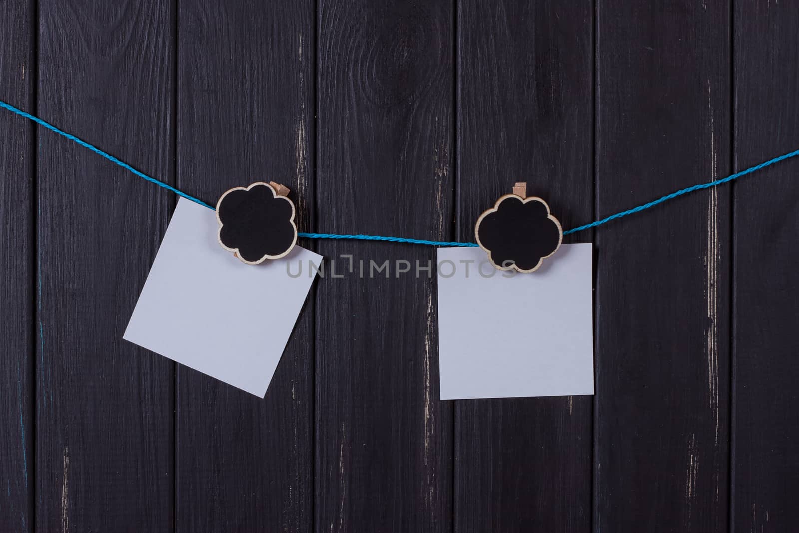 Clothespins, papers with a place for inscription on a black wooden background