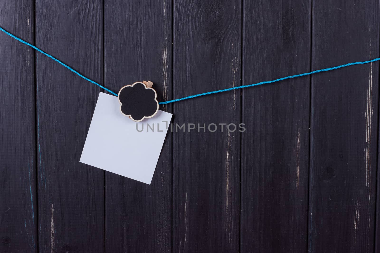 Clothespins, papers with a place for inscription on a black wooden background