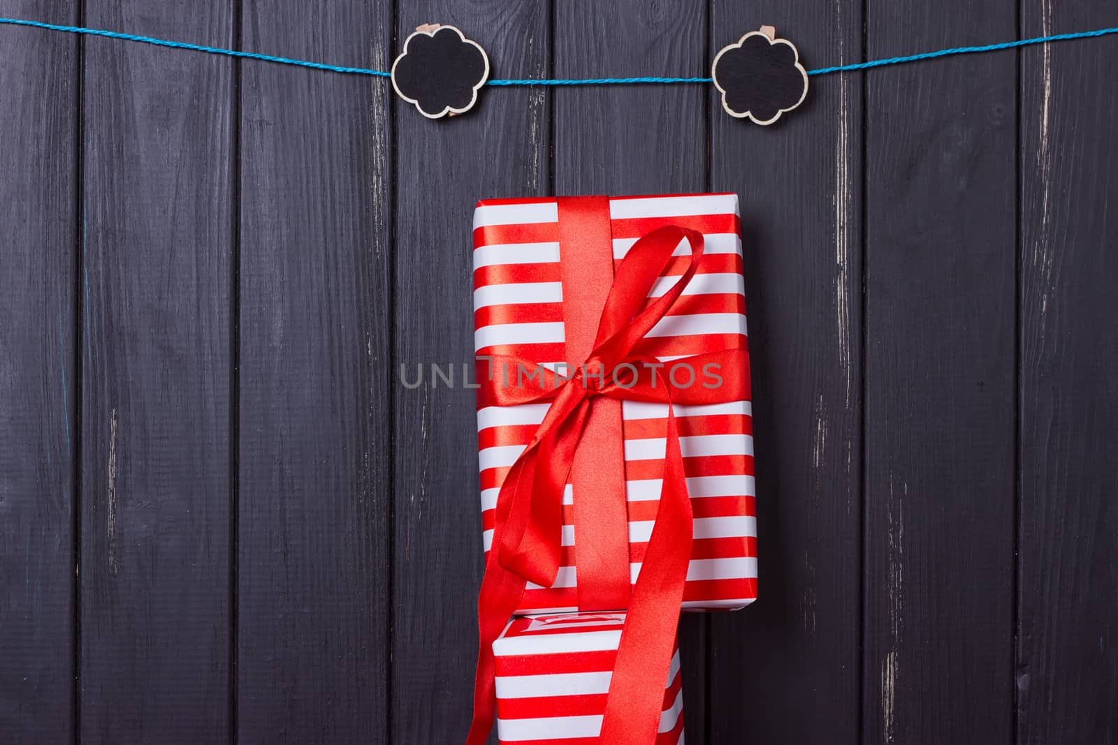 Gift box with a red bow on a wooden background With clothes pegs and place for text