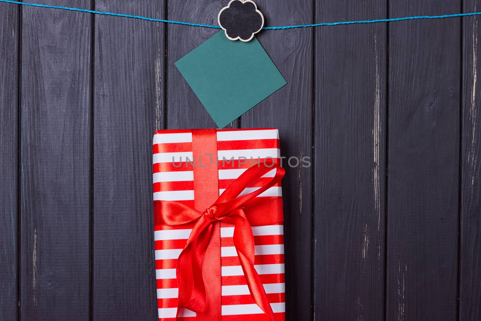 Gift box with a red bow on a wooden background With clothes pegs and place for text