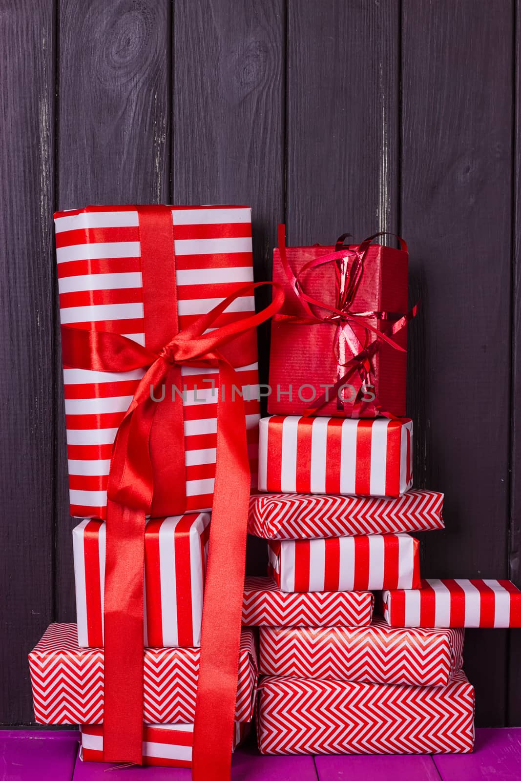 a slide of gifts in a red and white wrapper against a black wooden fence. Christmas presents