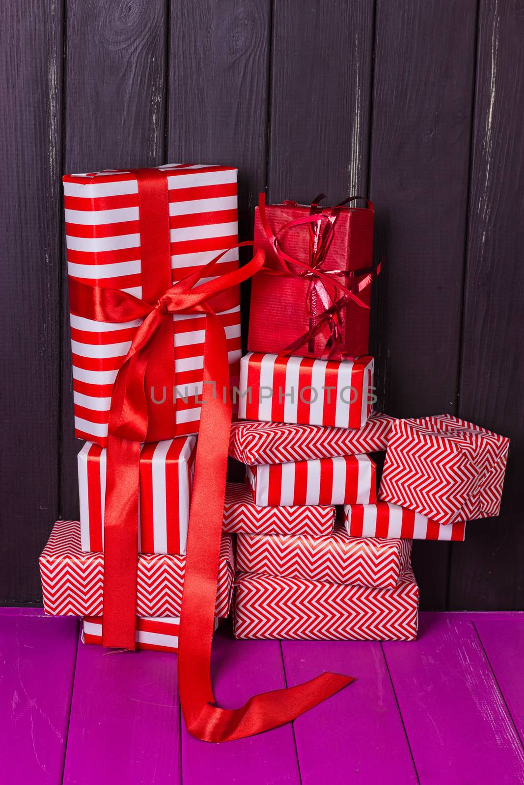 a slide of gifts in a red and white wrapper against a black wooden fence. Christmas presents