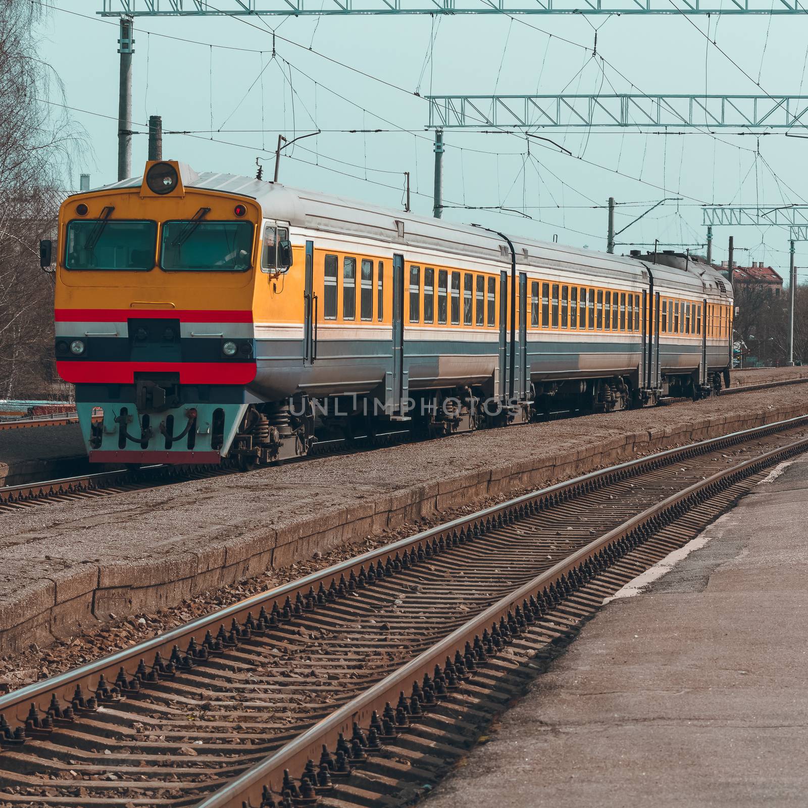 Old yellow passenger diesel train moving at the terminal