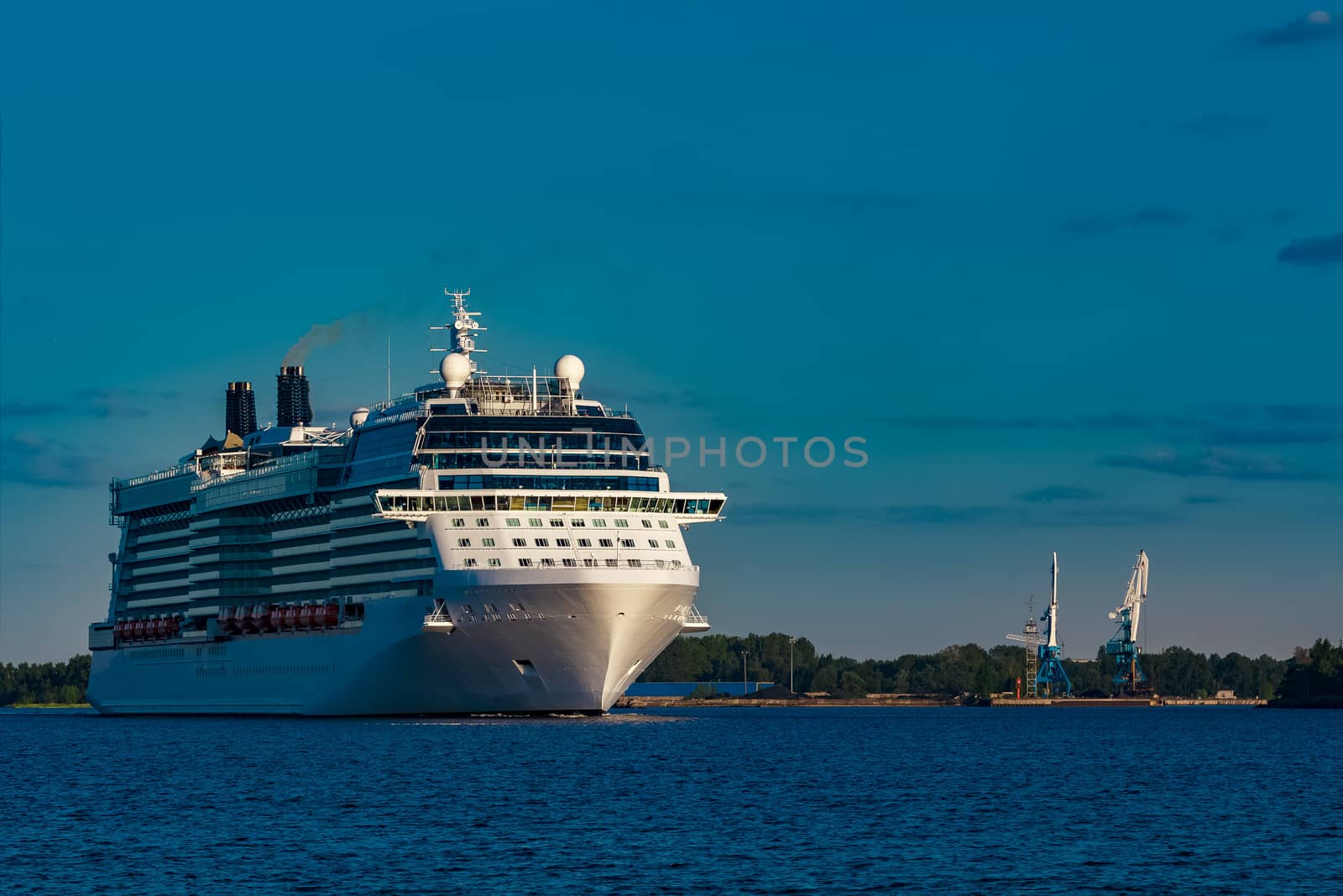 Giant white passenger ship moving past the port on a clear day