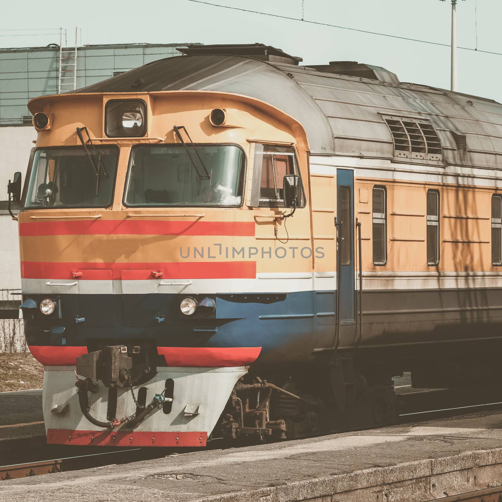 Old yellow passenger diesel train moving at the terminal