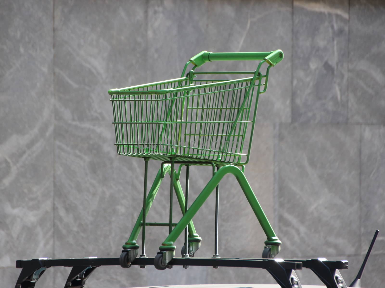 Green Shopping Trolley Isolated Mounted on Car Rooftop