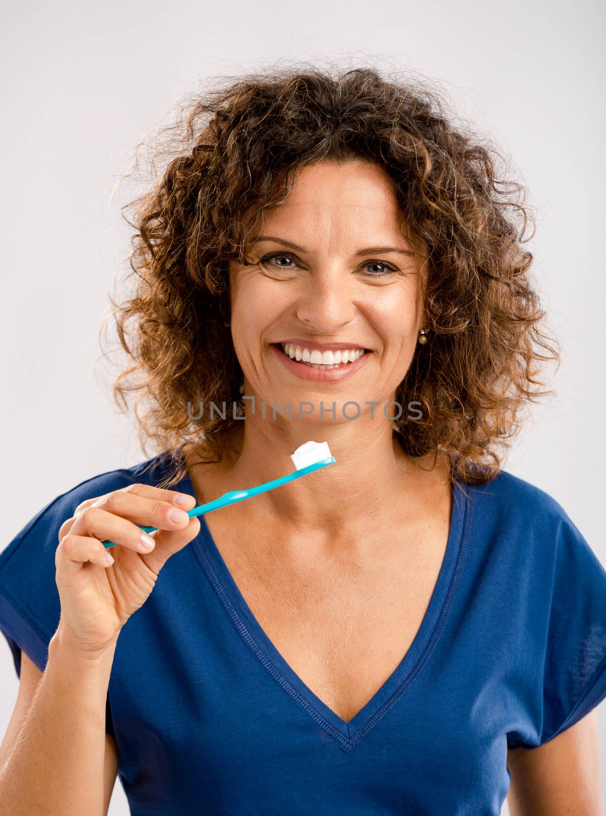 Beautiful mature woman brushing her teeths 