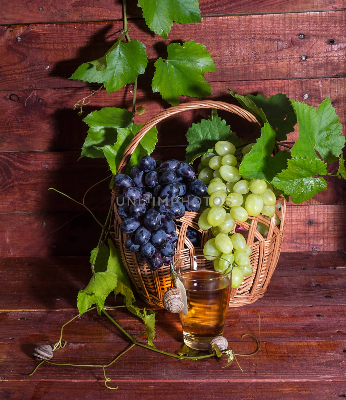 grape juice in a glass on a table with grapes and vine