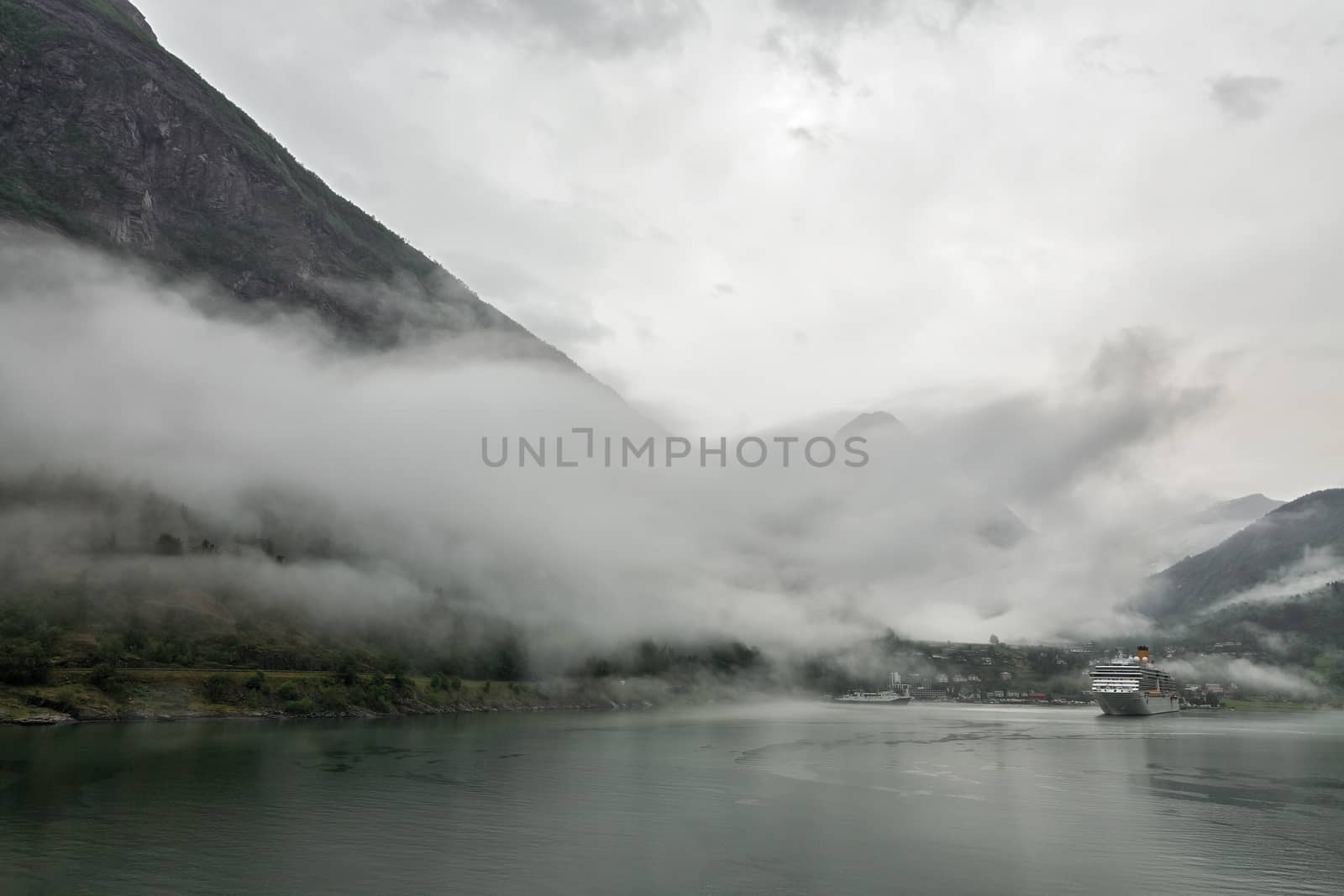 Cruise ship docked in Geiranger in a foggy and cloudy day, Norway