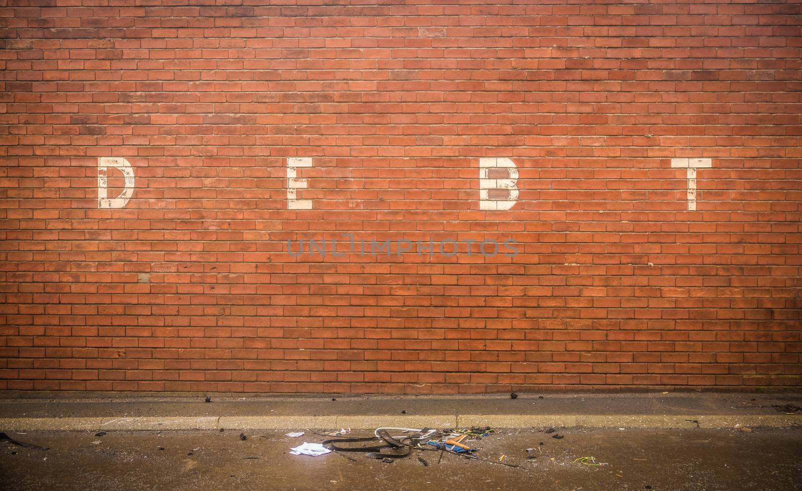 Grungy Red Brick Wall With The Word Debt