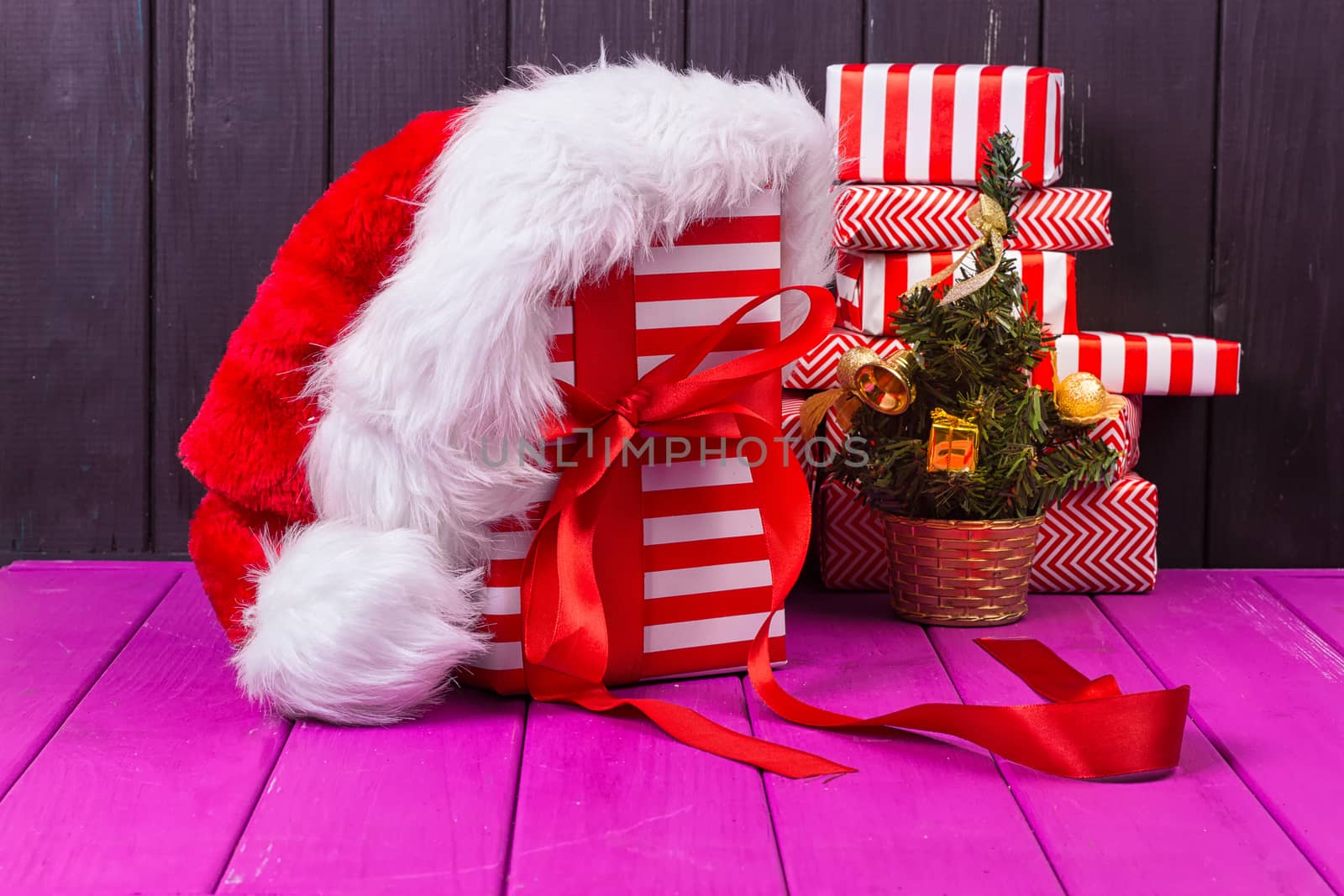 Gift boxes and small decorated Christmas tree and a Christmas cap on black background