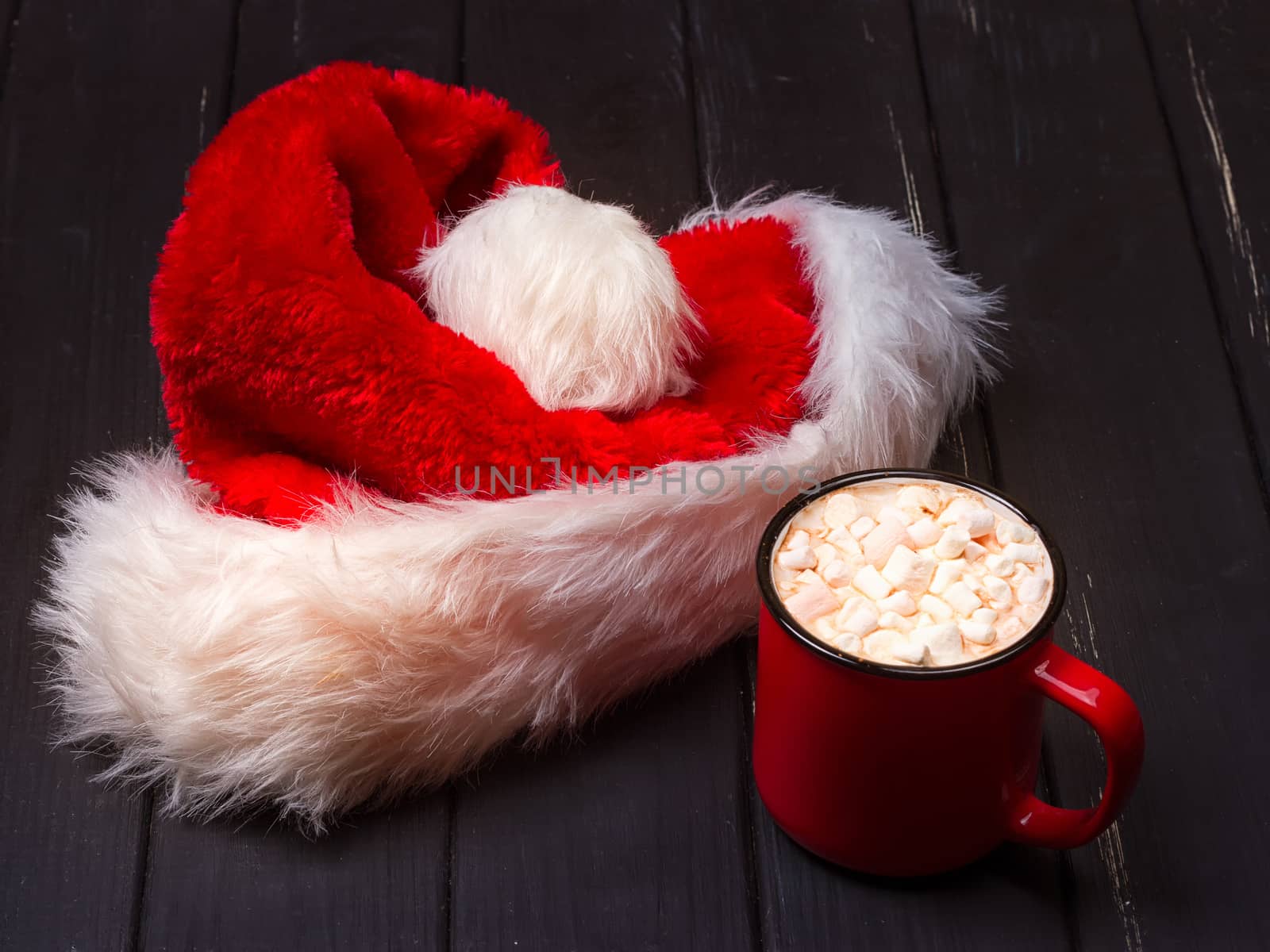 Hot chocolate with marshmallows and cap santa on grunge dark table