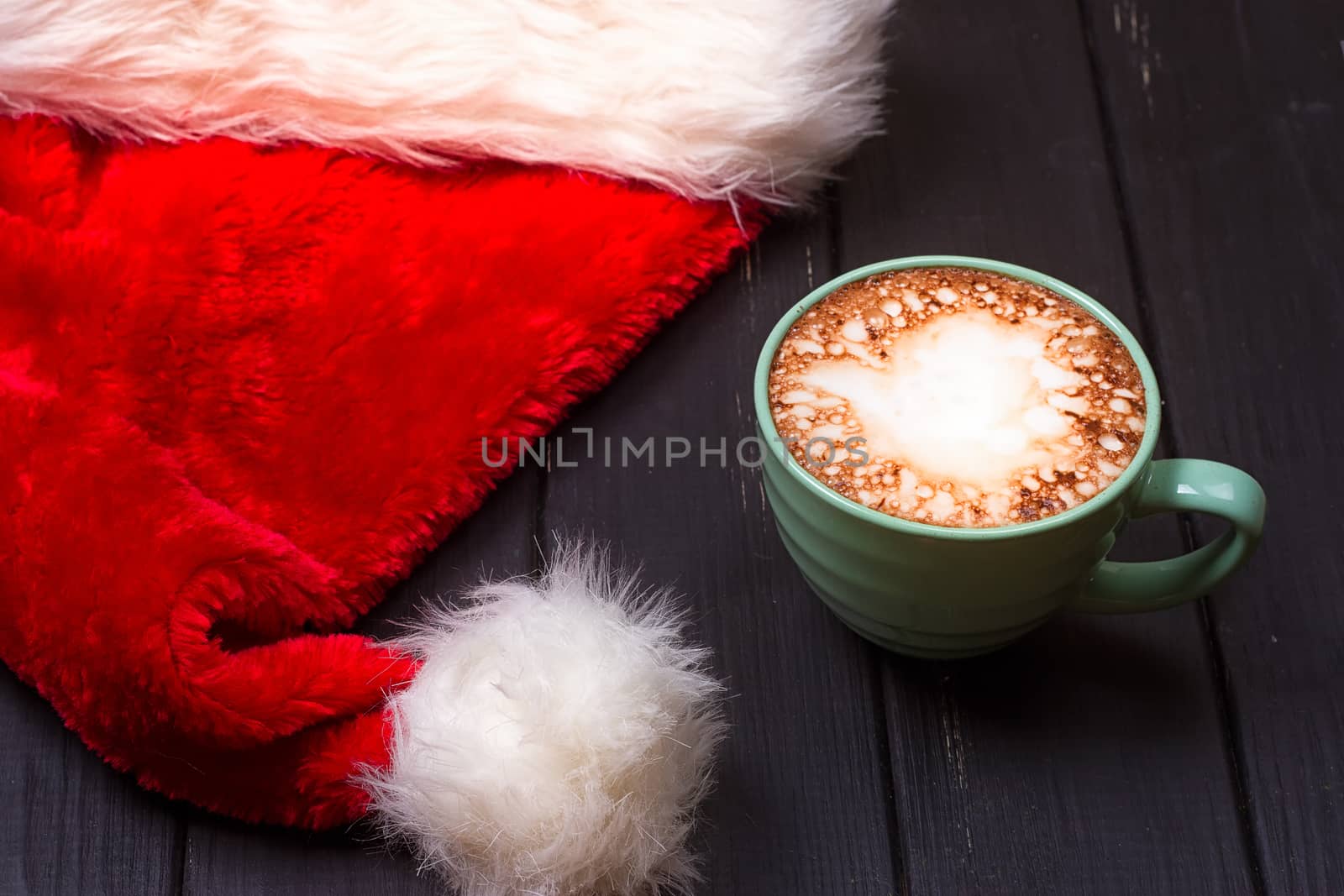 Hot chocolate with marshmallows and cap santa on grunge dark table