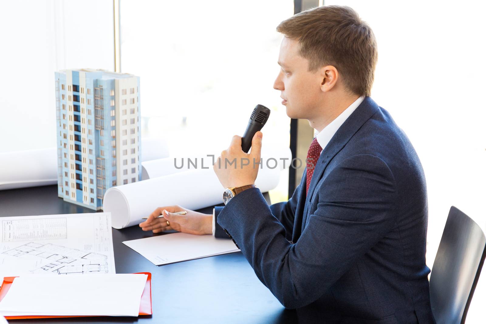 Business presentation of architect and investors, model of modern multi storey residential building house on table