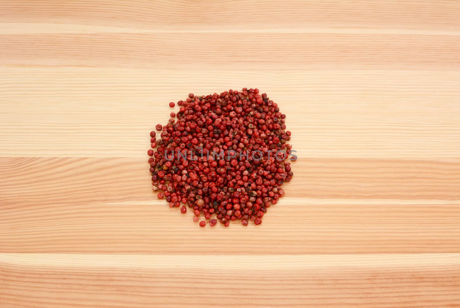 Pink peppercorns on a wooden background, pine wood grain