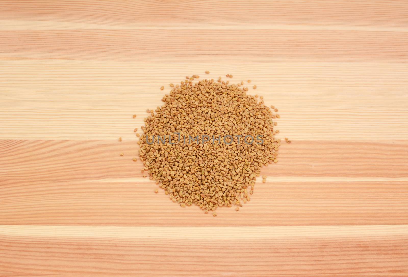 Fenugreek seeds on a wooden background, pine wood grain