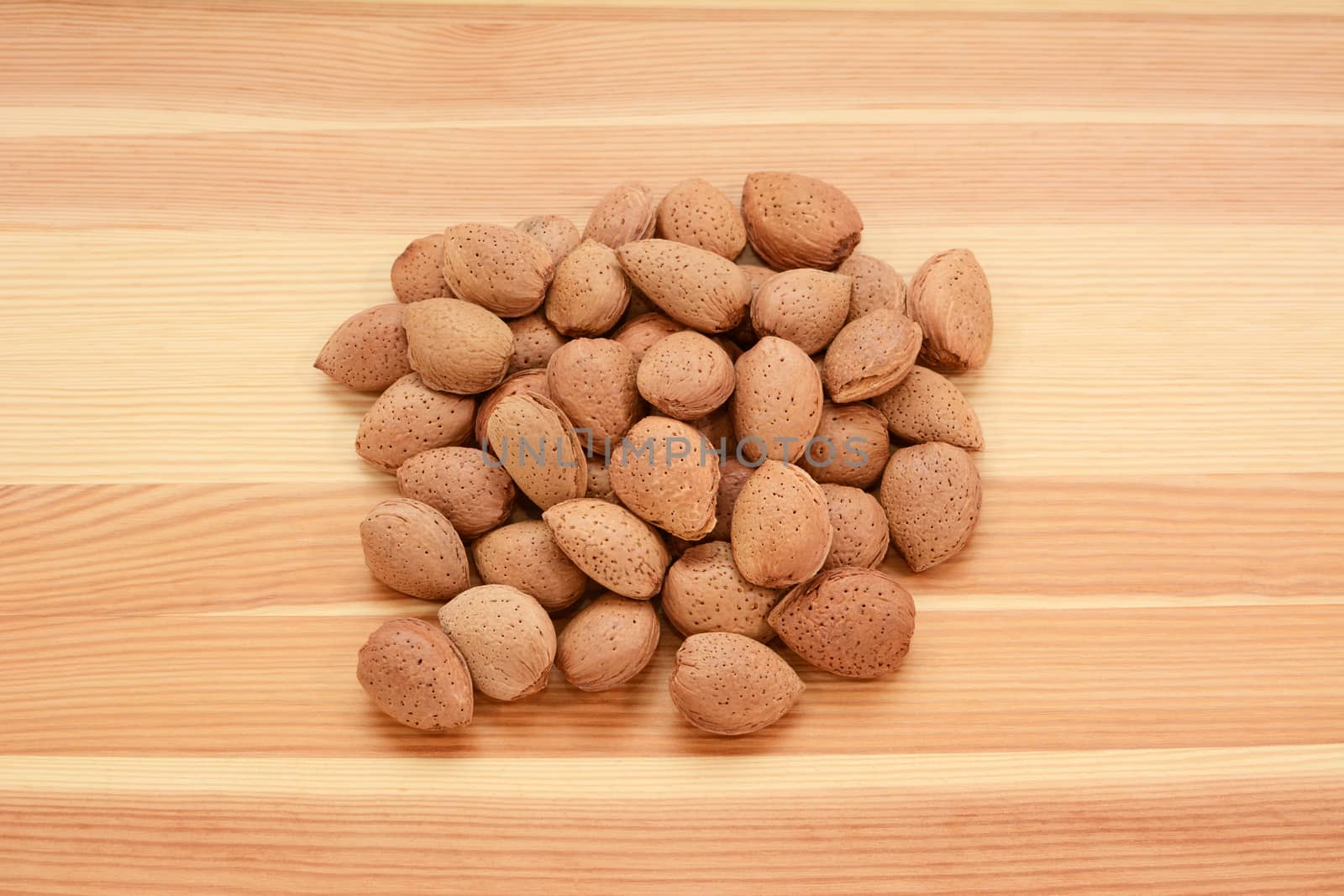 Almonds in shells on a wooden background, pine wood grain