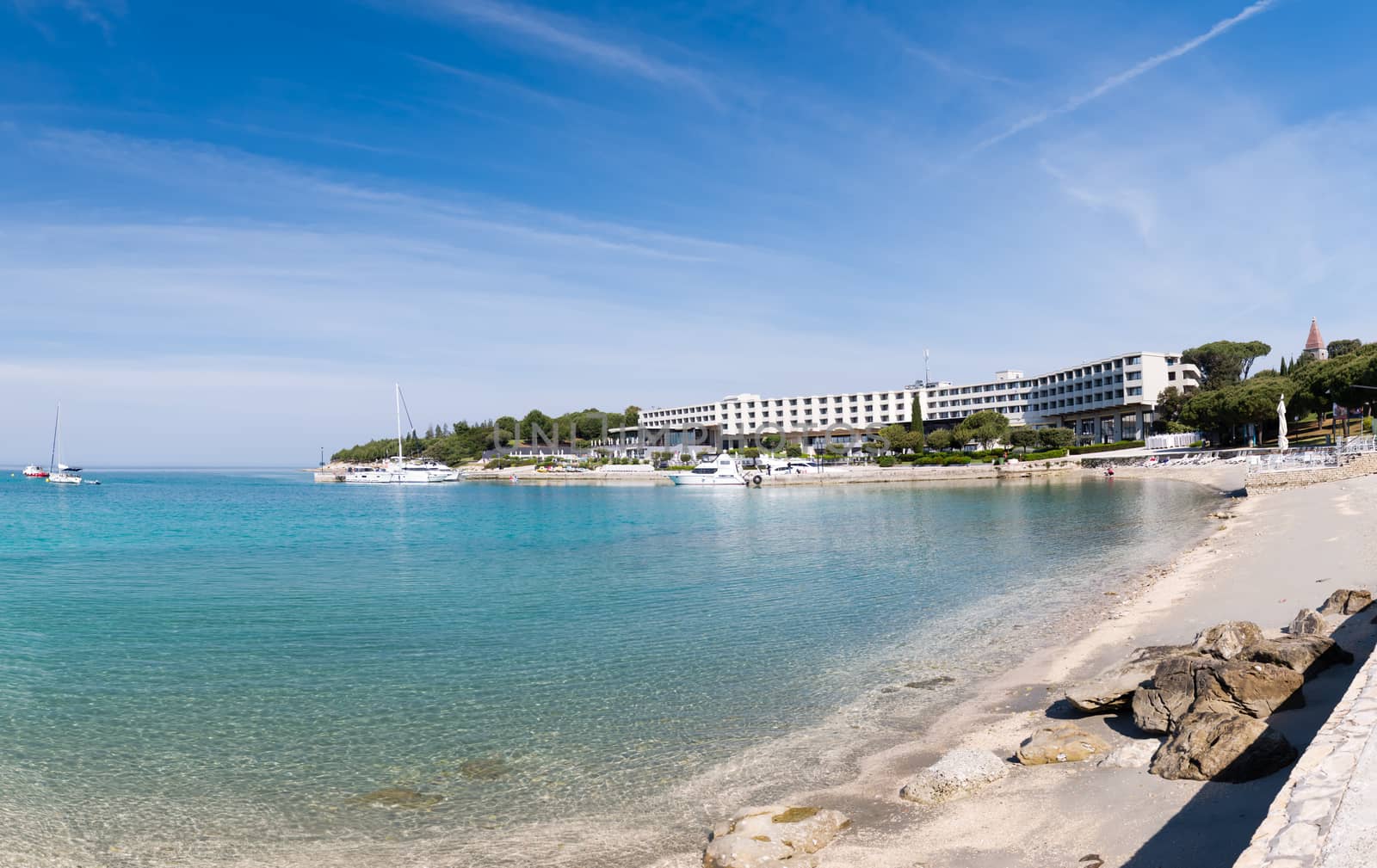 Seaside hotel with beach and turquoise water, Sveti Andrija or Red island near Rovinj, Croatia. A dike connects the island with Miskin island.