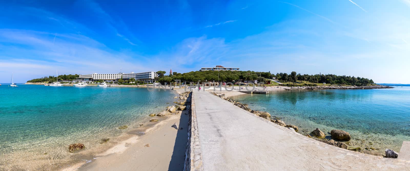 Seaside hotel with beach and turquoise water, Sveti Andrija or Red island near Rovinj, Croatia. A dike connects the island with Miskin island.