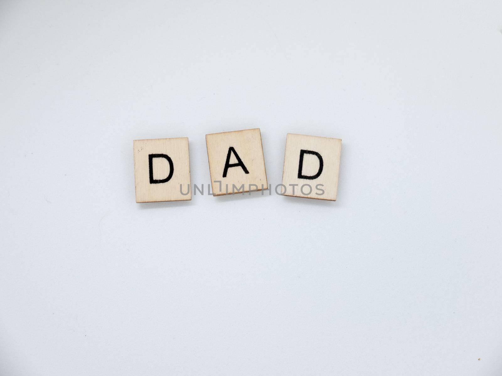 The word "Dad" spelled out with wooden letter tiles.
