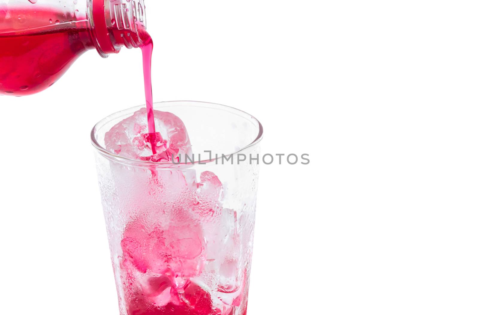 Closeup pouring  red soft drink with strawberry flavor into the glass on white background