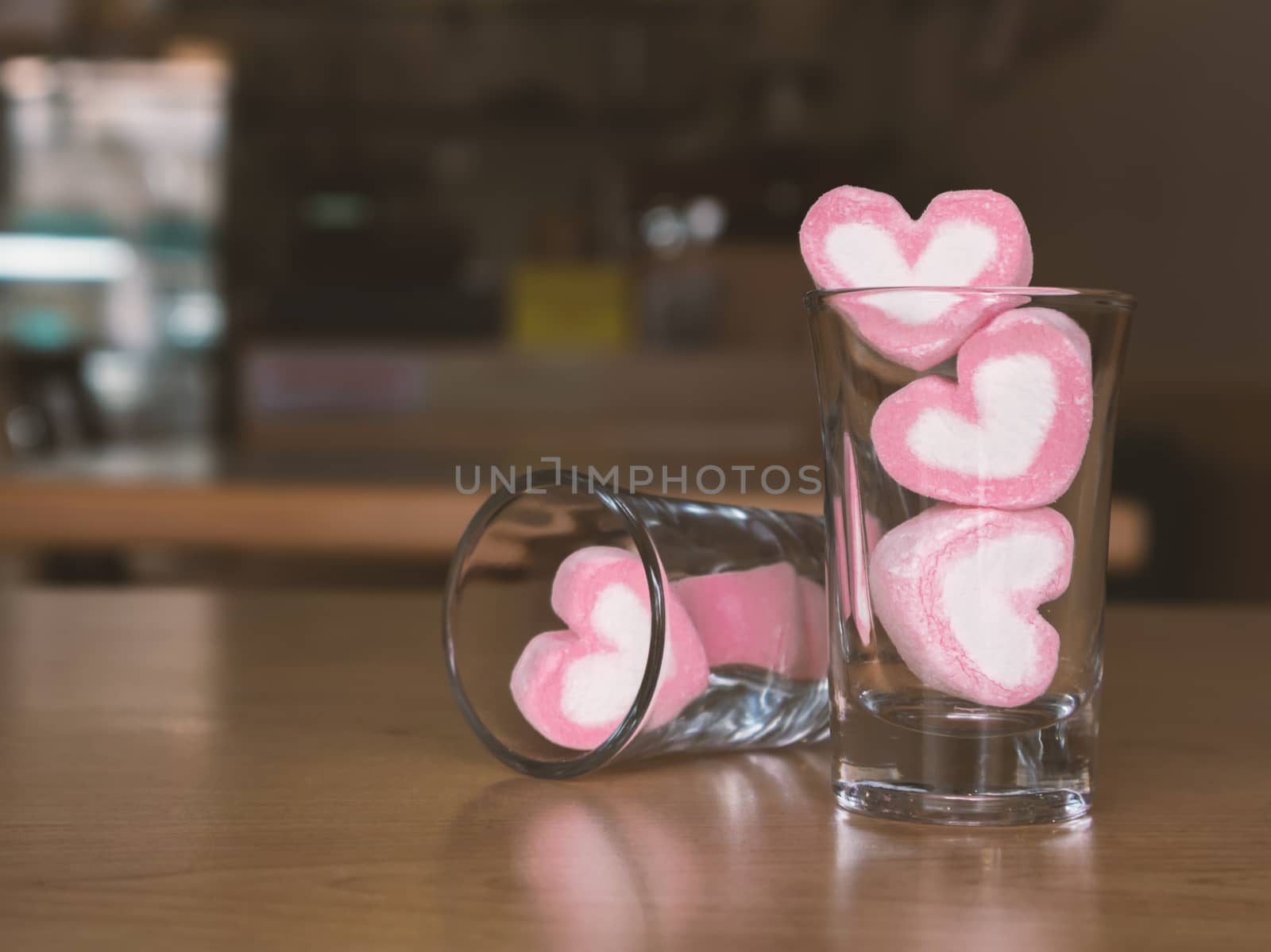Marshmallow pink heart shape in glass on wood table background, vintage tone