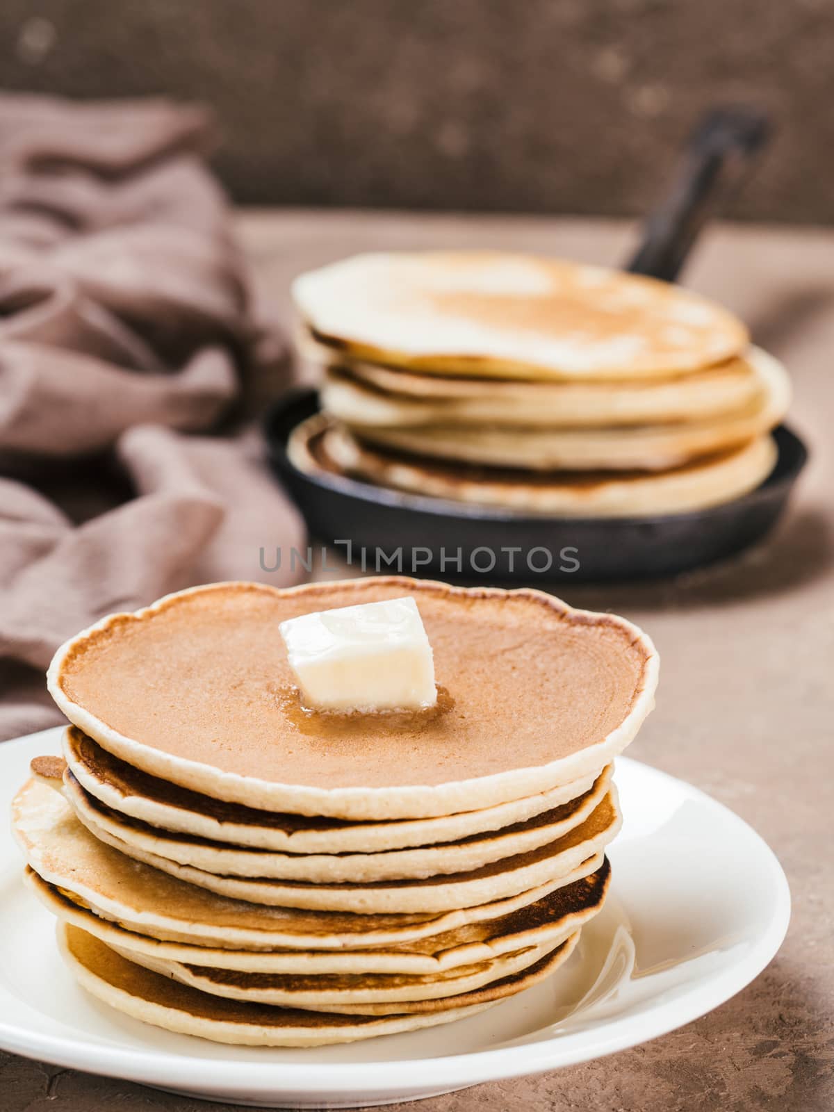 Close up view of homemade pancakes. Stack of pancakes with butter on brown concrete background.