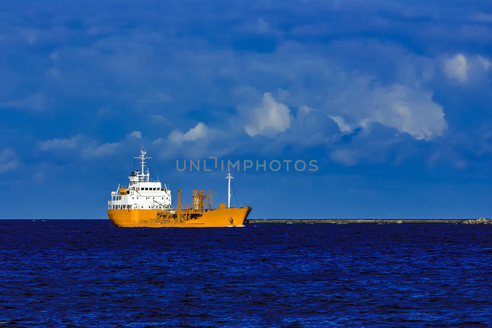 Yellow cargo tanker ship moving at the clear summer day