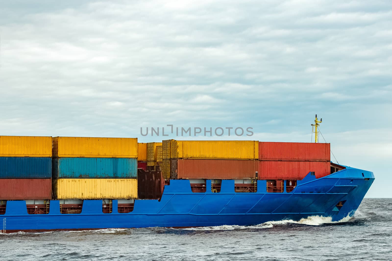 Blue cargo container ship fully loaded underway