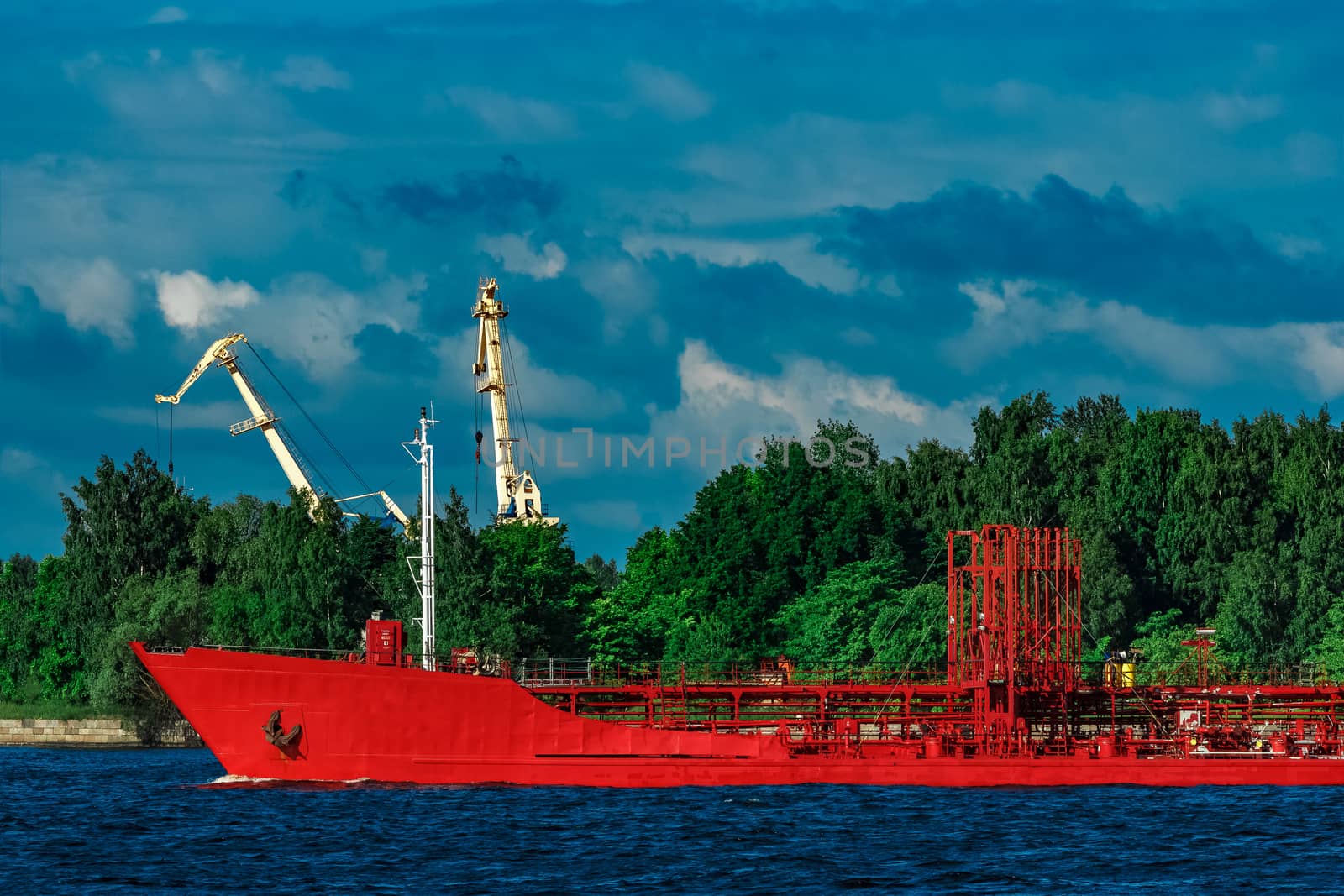 Red cargo tanker ship moving by the river