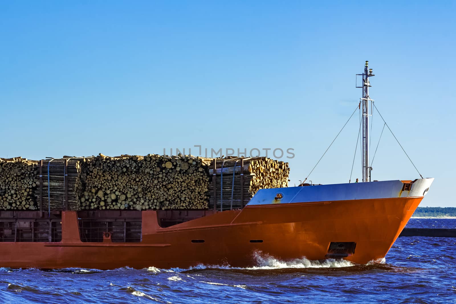 Orange bulk carrier sailing in clear summer day