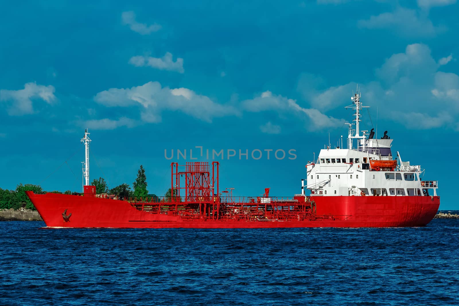 Red cargo tanker ship moving by the river