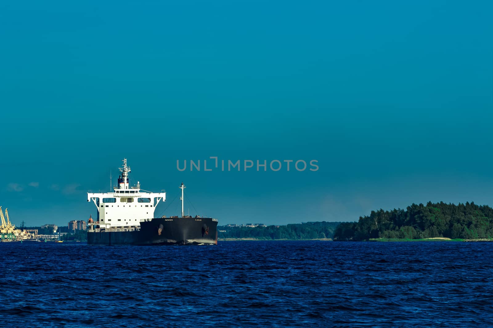 Black cargo ship moving to Baltic sea at clear day
