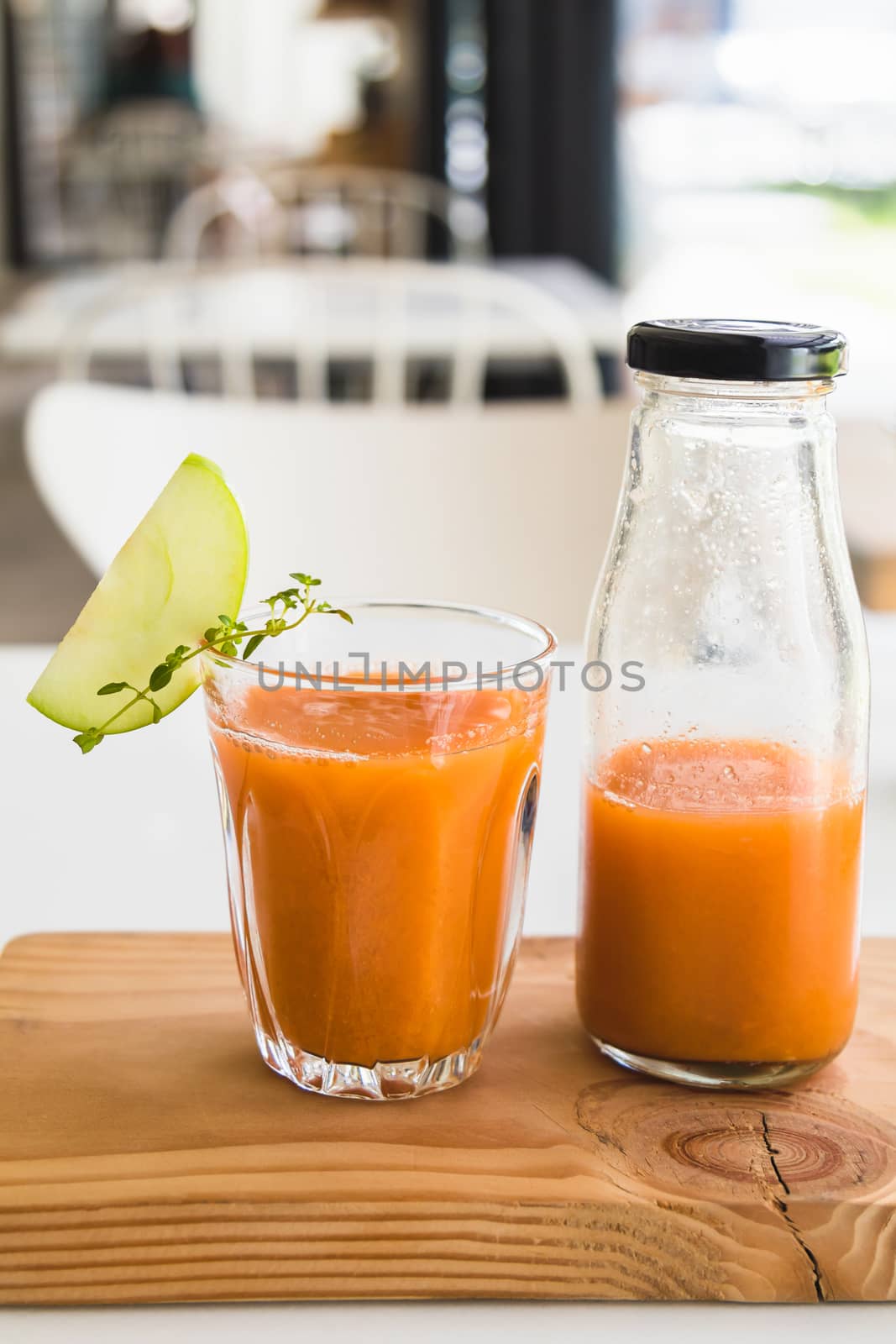 Glass of fresh juice with sliced green apple on wooden board
