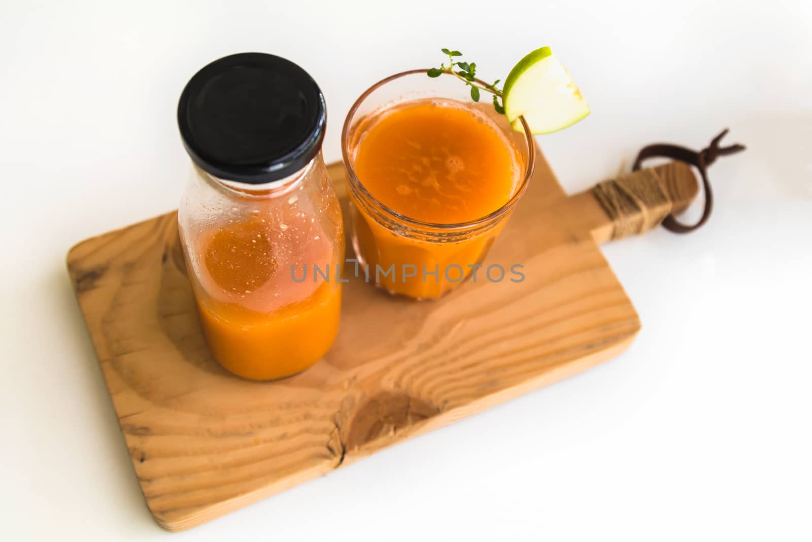 Glass of fresh juice with sliced green apple on wooden board