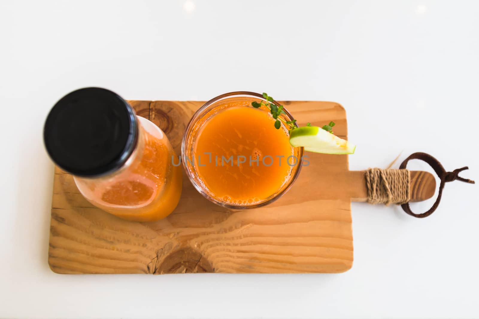 Glass of fresh juice with sliced green apple on wooden board