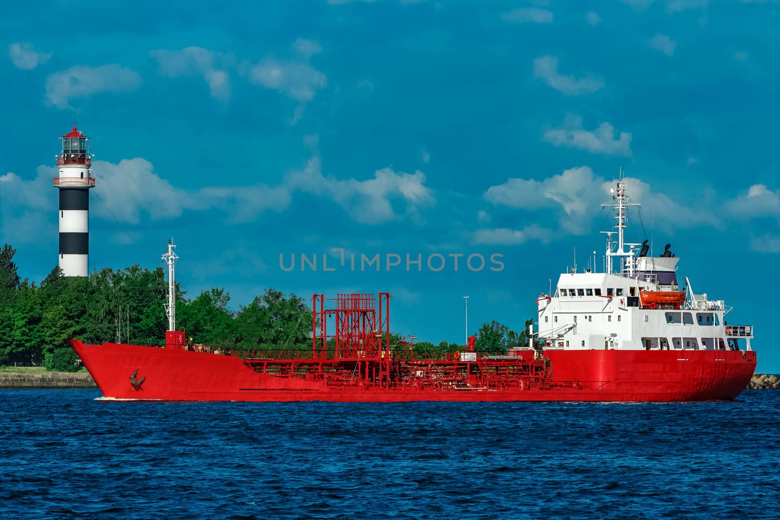 Red cargo tanker ship moving by the river