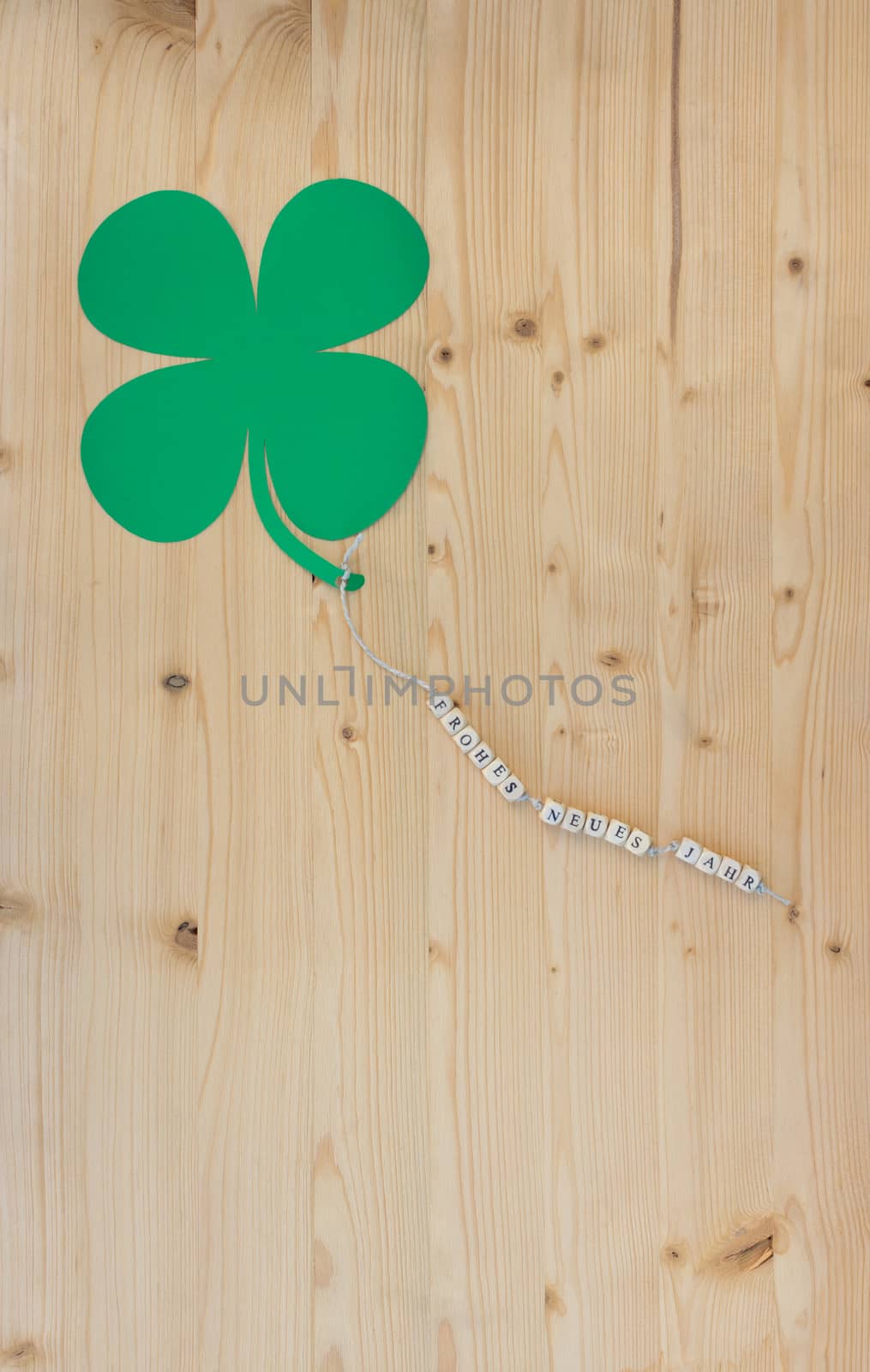 The german words for Happy New Year and a cloverleaf on a cord on wood