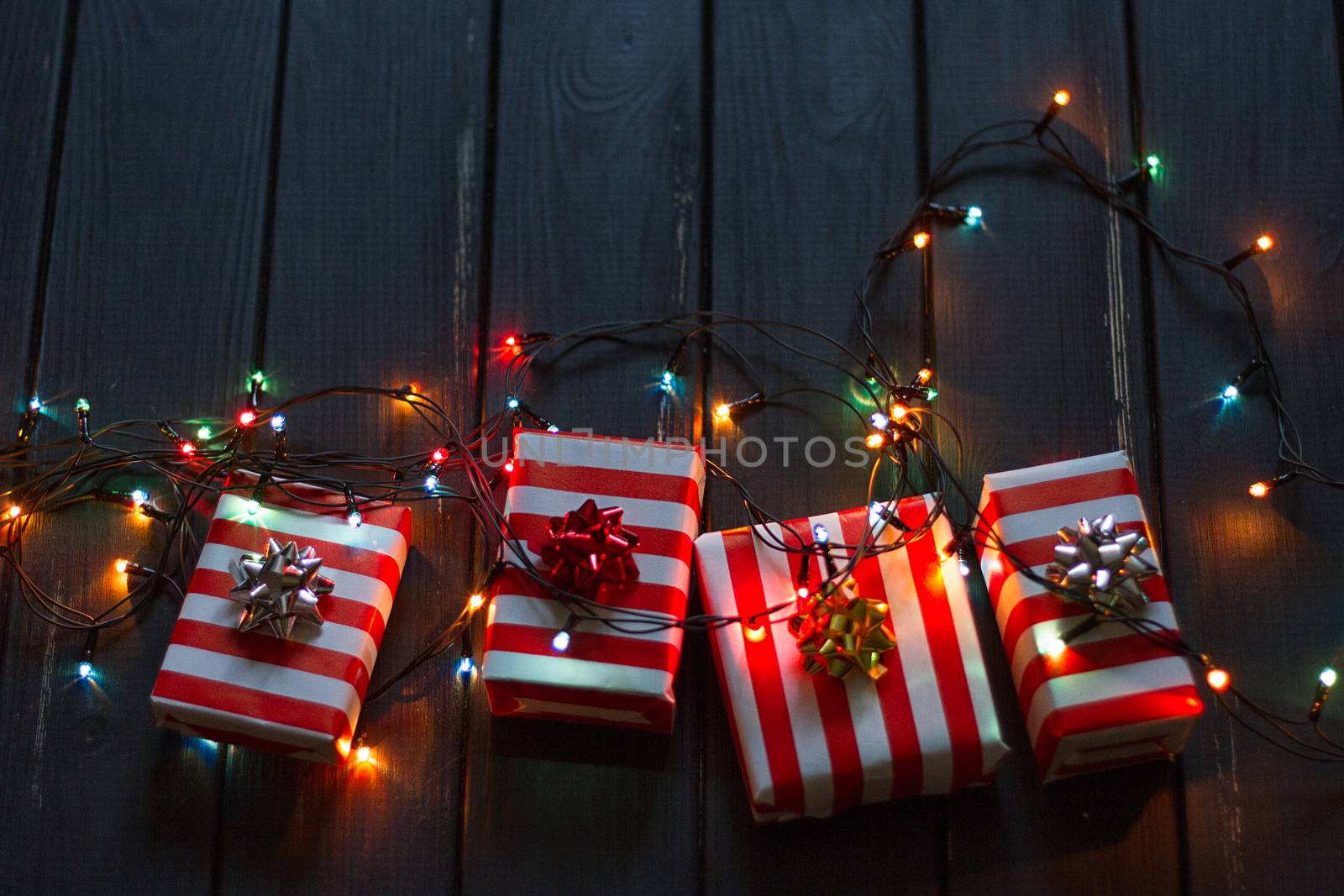 Gift box and garland lights over old wooden background