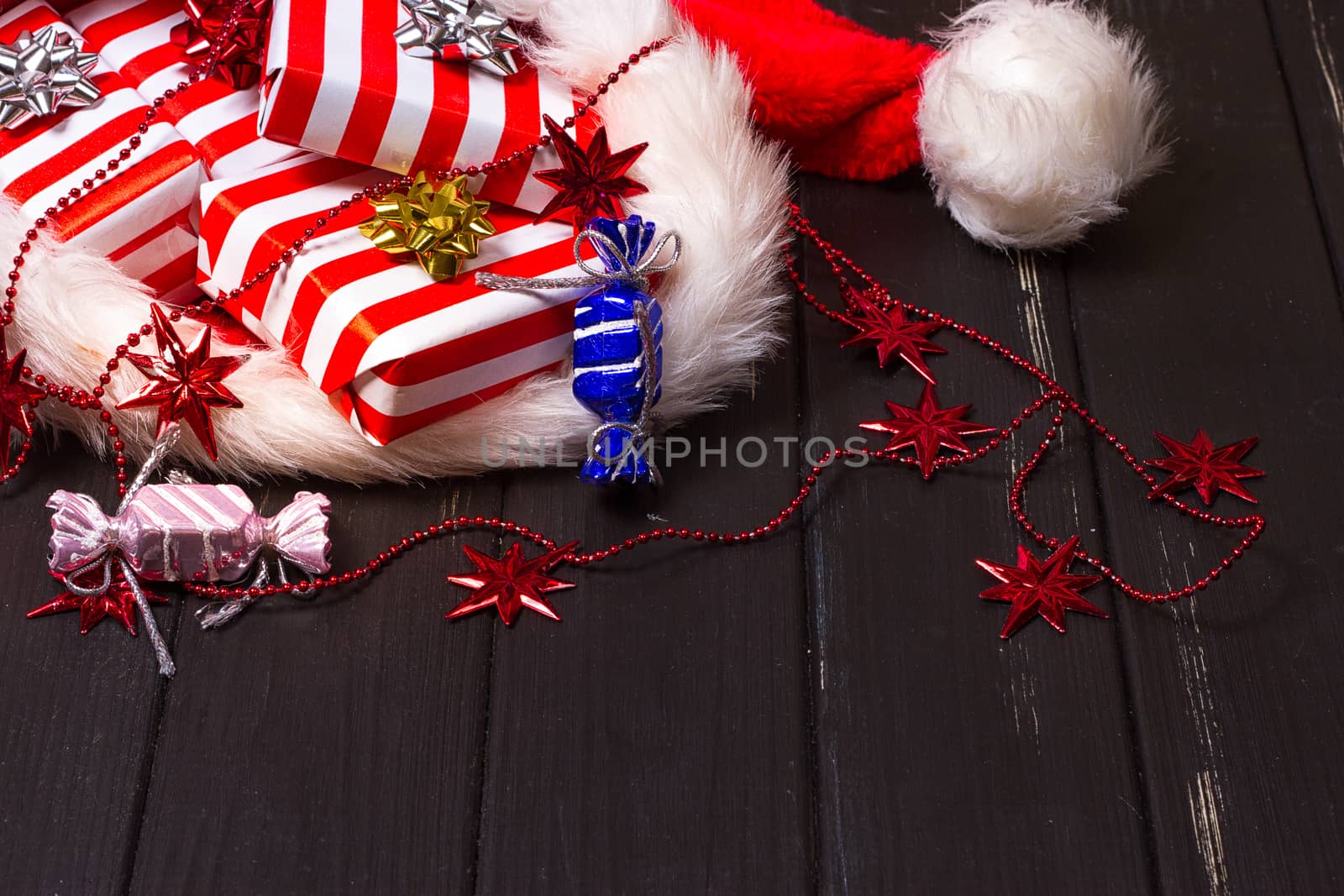 Christmas gifts in a Santa Claus hat on a black wooden background