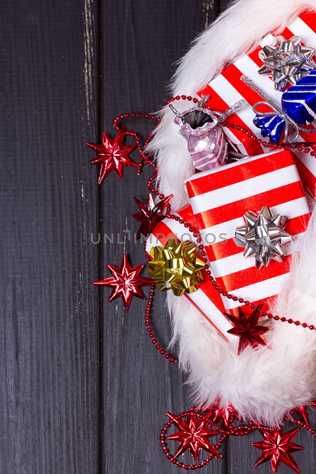 Christmas gifts in a Santa Claus hat on a black wooden background